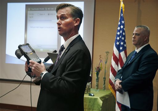 Lewis Koski, left, chief investigator of the Colorado Marijuana Enforcement Division, demonstrates a handheld radio-frequency reader, which is part of its new marijuana inventory tracking system, known as MITS, during a news conference, in Denver, Wednesday, Dec. 11, 2013. Ron Kammerzell, the senior director of enforcement for the Colorado Dept. of Revenue, is pictured at right. Roughly 150 Colorado medical marijuana dispensaries are hoping to begin selling to recreational users when it becomes legal to sell on Jan. 1, 2014. (AP Photo/Brennan Linsley)