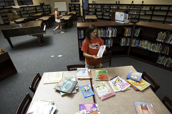 Katie Peoples (front), 13, helps set up the new library Monday morning, July 30 at Black Forest Hills Elementary School. Technology will be a prominent part of learning at Black Forest Hills. All classrooms have a Smart Board, a projector, and access to the wireless network. (Marla R. Keown/Aurora Sentinel)