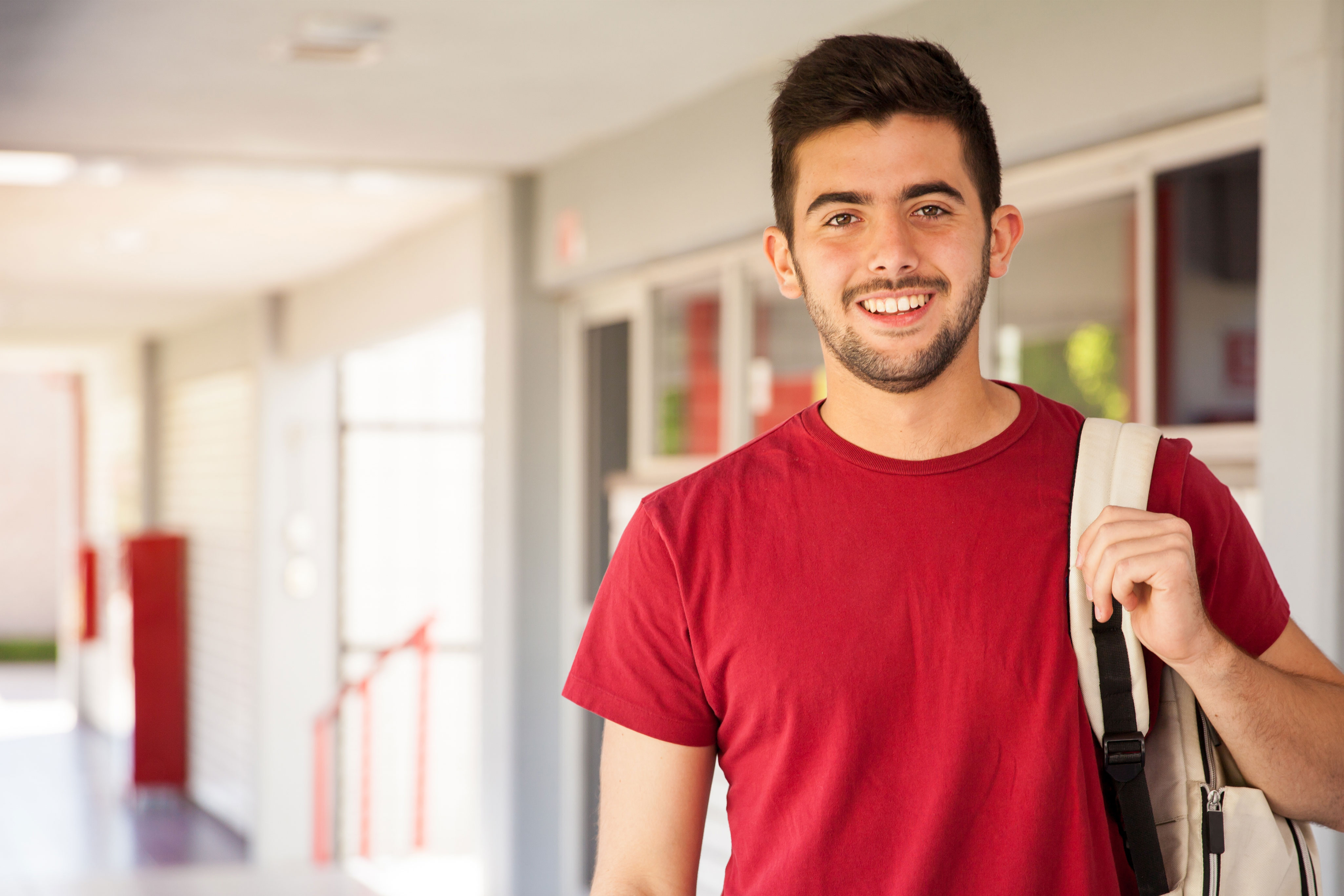 young man holding backpack in hallway