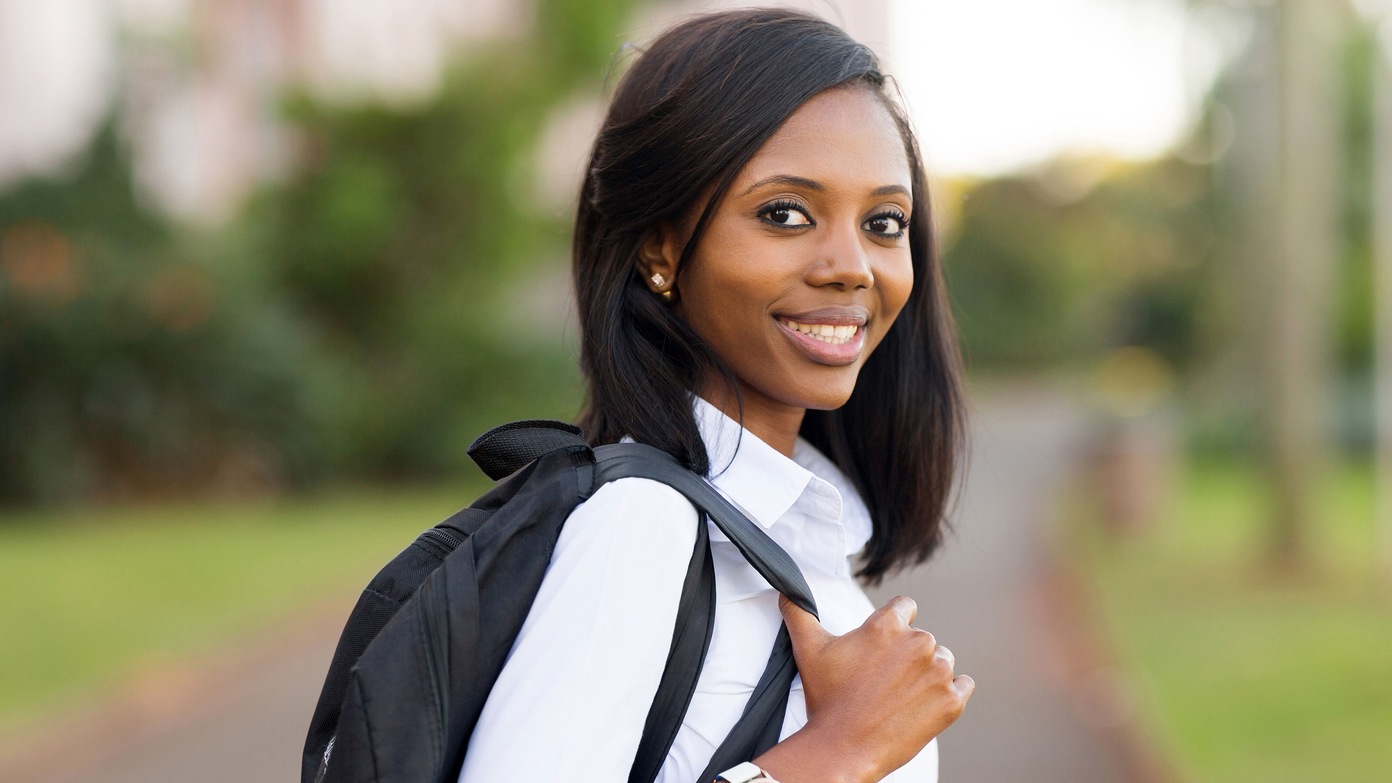female student holding backpack smiles at camera