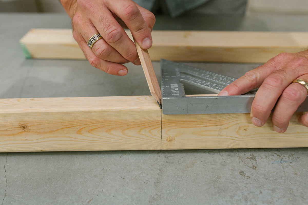 Measuring and marking board with speed square and pencil.