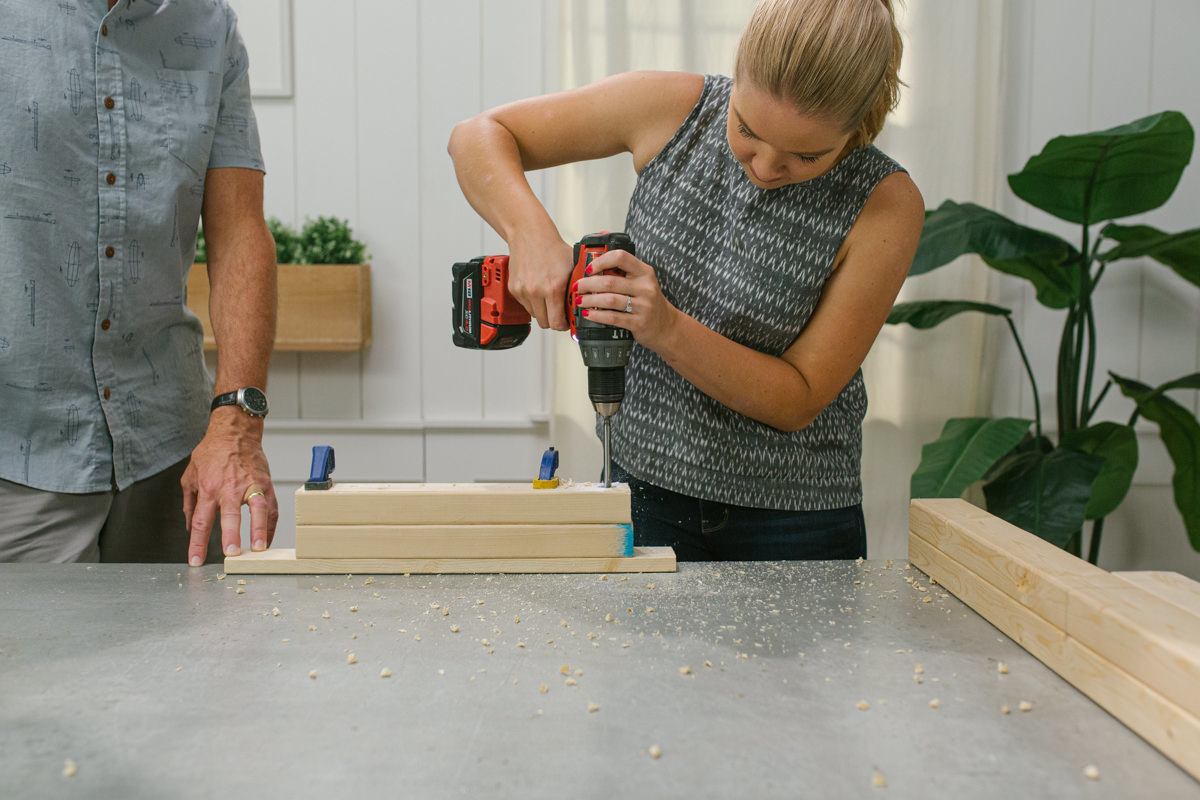 Drilling hole in board clamped to scrap wood.