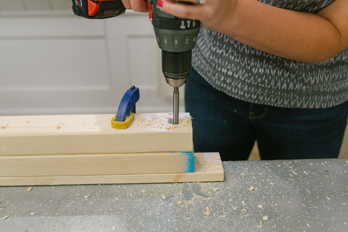 Drilling hole in board clamped to scrap wood.