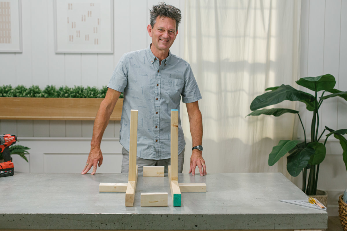 Two DIY wooden mini trebuchet side assembly set up with small wood pieces between them at each end.