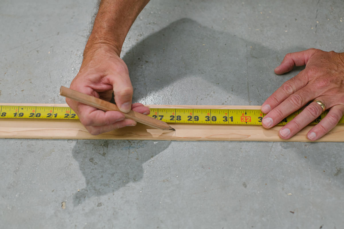 Measuring and marking wedge moulding with measuring tape and pencil.