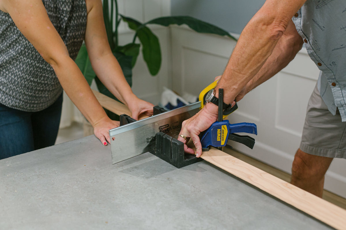 Cutting clamped wedge moulding with miter box and handsaw.