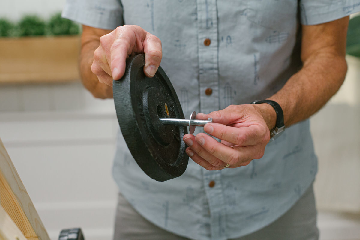 Threading large hex bolt and washer through disc weight.