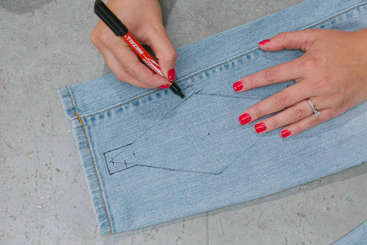 Drawing the sling outline, diamond shape with small rectangle on the acute corners, on denim with pen.