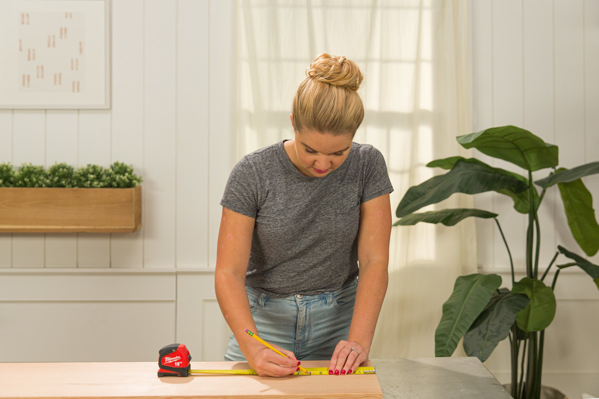 Measuring and marking doug fir board with measuring tape and pencil.