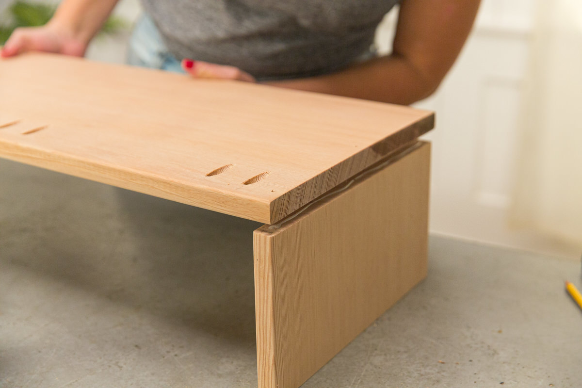 Connecting doug fir boards at right angle with wood glue to create corner of wood DIY coffee table assembly.