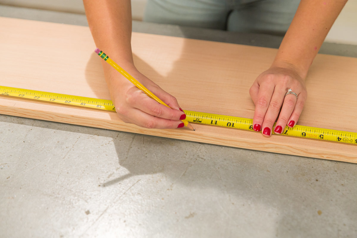 Measuring and marking doug fir board with measuring tape and pencil.