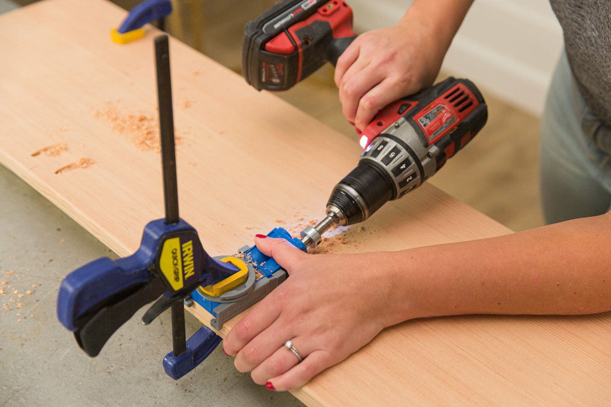 Drilling pocket hole in doug fir board with clamped Kreg jig and power drill.