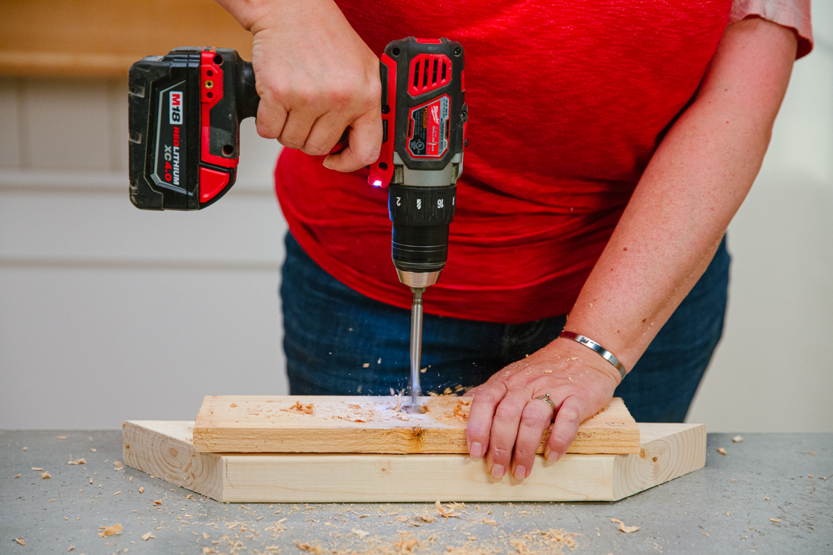 Drilling hole in board with power drill.