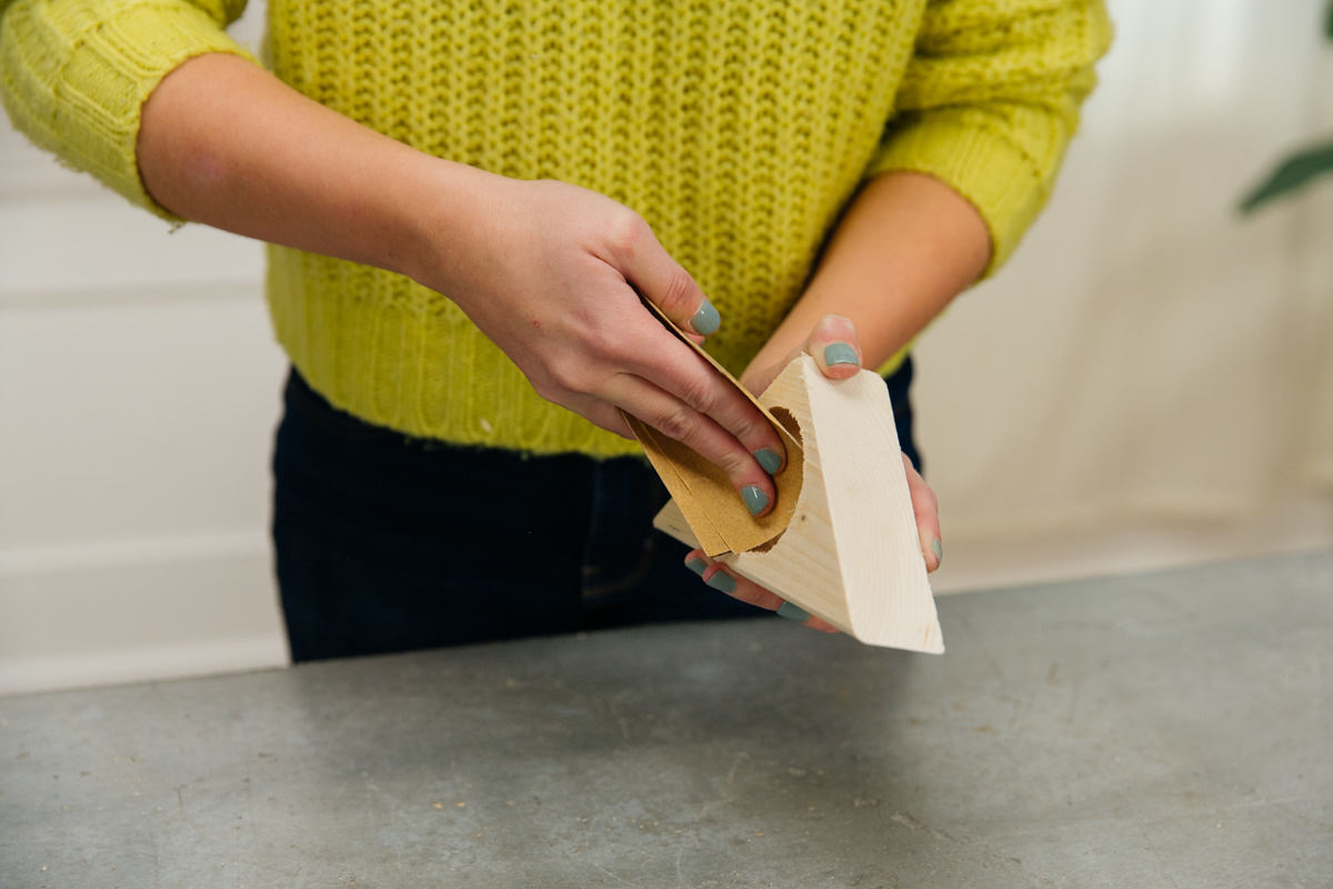 Sanding inside of DIY wooden mini succulent planter body hole with sandpaper.