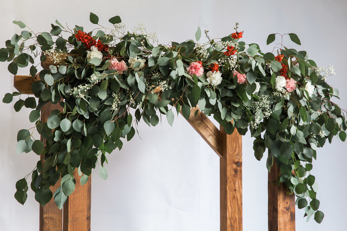 Flower-topped wood DIY wedding arch, which is stained with Perofin Verde Bitterwood.