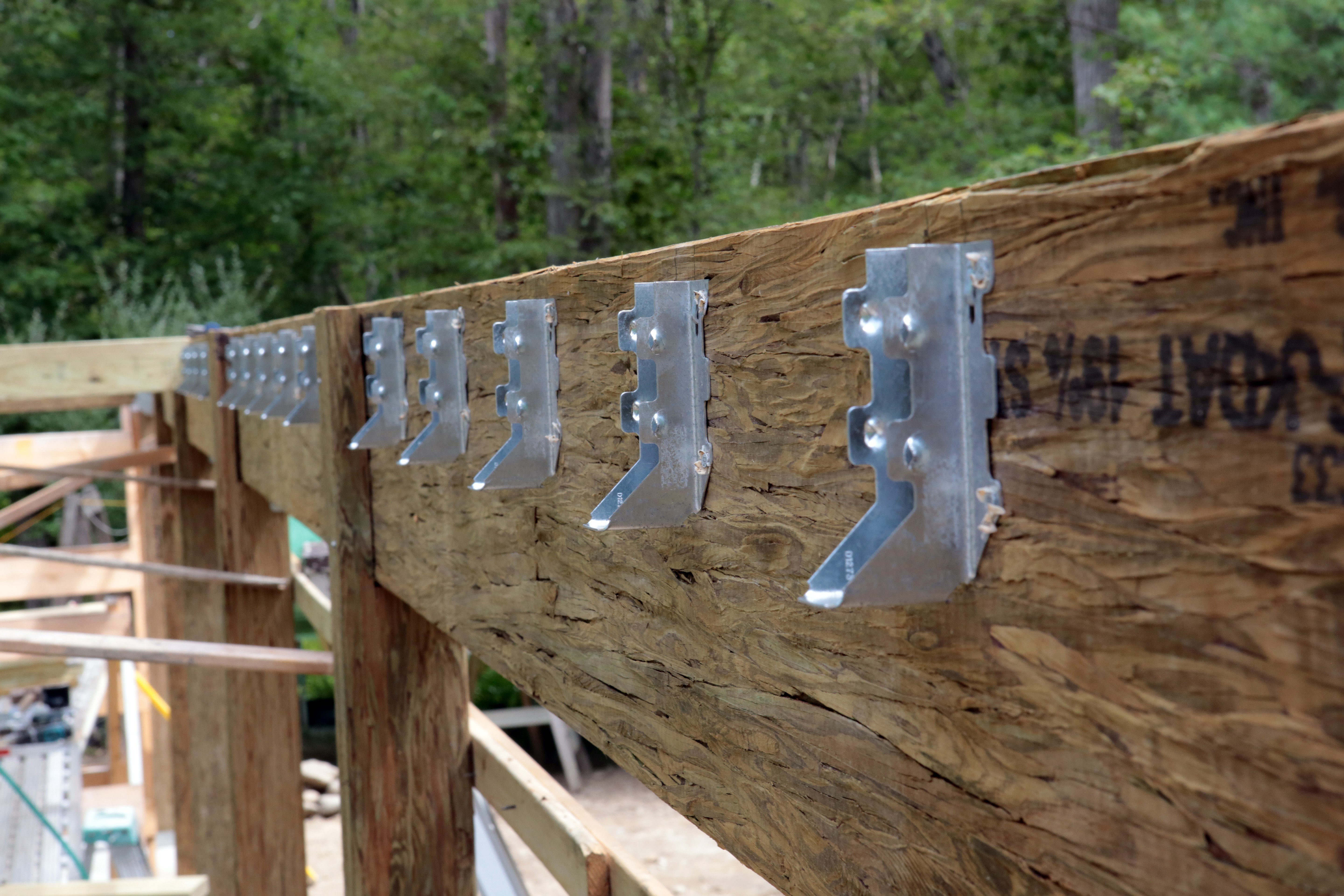 Joist hangers installed in a rim joist of a deck under construction.