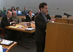 Jonathon Lowy of the Brady Center to Prevent Gun Violence as opposing counsel Tony Sholty, defendant Ray Coxe, and attorney Leal Harrison listen in the background.