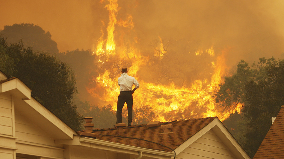 Standing on a rooftop, a man looks at the Springs fire's approaching flames in California Friday. The wildfire, reportedly, 20 percent contained, might be weakened by high humidity and cooler temperatures Saturday. David McNew/Getty Images Standing on a rooftop, a man looks at the Springs fire's approaching flames in California Friday. The wildfire, reportedly, 20 percent contained, might be weakened by high humidity and cooler temperatures Saturday. David McNew/Getty Images
