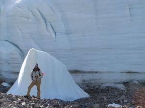As the Teardrop Glacier on Ellesmere Island in the Canadian Arctic recedes, researchers have found a kind of evergreen plant called bryophytes coming out from beneath the ice. Here, a researcher stands next to part of the glacier for scale. Courtesy of Catherine La Farge As the Teardrop Glacier on Ellesmere Island in the Canadian Arctic recedes, researchers have found a kind of evergreen plant called bryophytes coming out from beneath the ice. Here, a researcher stands next to part of the glacier for scale. Courtesy of Catherine La Farge