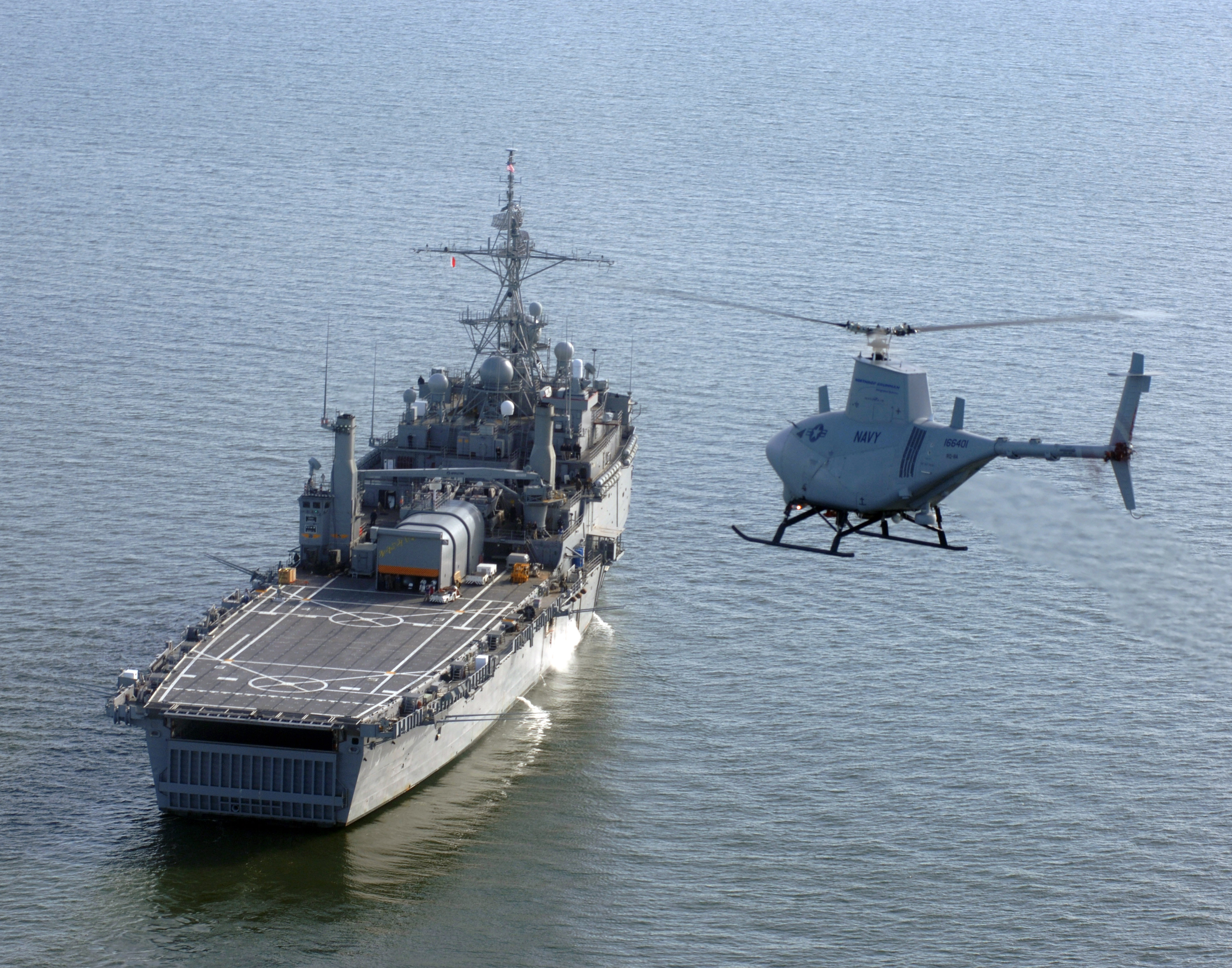 A U.S. Navy RQ-8A Fire Scout Vertical Takeoff and Landing Tactical Unmanned Aerial Vehicle (VTUAV) System prepares to land aboard the amphibious transport dock ship USS Nashville (LPD 13). This is the first autonomous landing of the Fire Scout aboard a Navy vessel at sea. With an on-station endurance of over four hours, the Fire Scout system is capable of continuous operations, providing coverage at 110 nautical miles from the launch site. Utilizing a baseline payload that includes electro-optical/infrared sensors and a laser rangefinder/designator, Fire Scout can find and identify tactical targets, track and designate targets, accurately provide targeting data to strike platforms, employ precision weapons, and perform battle damage assessment. A U.S. Navy RQ-8A Fire Scout Vertical Takeoff and Landing Tactical Unmanned Aerial Vehicle (VTUAV) System prepares to land aboard the amphibious transport dock ship USS Nashville (LPD 13). This is the first autonomous landing of the Fire Scout aboard a Navy vessel at sea. With an on-station endurance of over four hours, the Fire Scout system is capable of continuous operations, providing coverage at 110 nautical miles from the launch site. Utilizing a baseline payload that includes electro-optical/infrared sensors and a laser rangefinder/designator, Fire Scout can find and identify tactical targets, track and designate targets, accurately provide targeting data to strike platforms, employ precision weapons, and perform battle damage assessment.