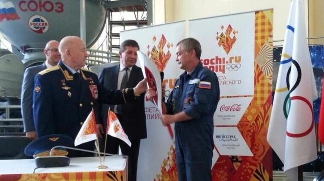 Former cosmonaut Alexey Leonov, left, the first man to perform a spacewalk, passed an Olympic torch to Mikhail Tyurin, who will lead the mission to the International Space Station in November. DChernyshenko/ Former cosmonaut Alexey Leonov, left, the first man to perform a spacewalk, passed an Olympic torch to Mikhail Tyurin, who will lead the mission to the International Space Station in November. DChernyshenko/