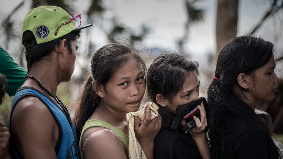 In Tacloban, the Philippines, on Thursday, some survivors waiting in a line to charge cellphones covered their faces because of the lingering smell of dead bodies. Philippe Lopez /AFP/Getty Images In Tacloban, the Philippines, on Thursday, some survivors waiting in a line to charge cellphones covered their faces because of the lingering smell of dead bodies. Philippe Lopez /AFP/Getty Images
