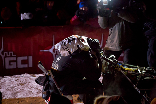Moments after arriving at the finish line, Dallas Seavey crouches down in his sled, overcome with emotion. (Photo by KNOM Radio Mission)
