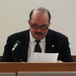 Cold case investigator Randel McPherron reads a report while on the stand on Friday in the Robert Kowalski homicide trial. (Photo by Matt Miller/KTOO)