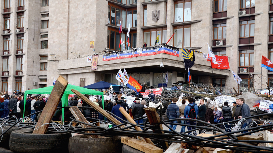 Pro-Russian protesters surround a barricade made by used tires and barbed wire Friday in Donetsk, Ukraine. Pro-Russian protesters took control of the government building and have held it since Sunday. The Asahi Shimbun via Getty Images