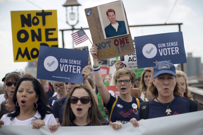 Demonstrators raise posters as they march across the Brooklyn Bridge to call for tougher gun control laws on Saturday in New York. John Minchillo/AP