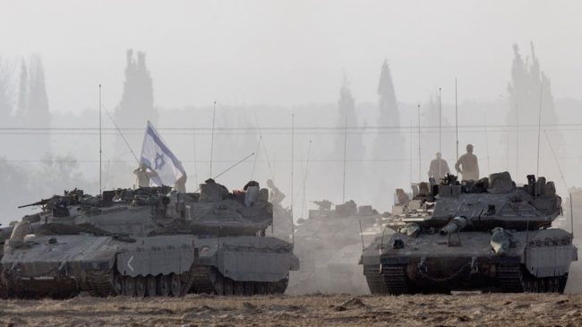 Israeli soldiers stand on their tanks near Israel's border with the Gaza Strip on Tuesday. Israeli warplanes pounded Gaza with more than 50 strikes overnight after Hamas militants fired scores of rockets over the border. Jack Guez/AFP/Getty Images