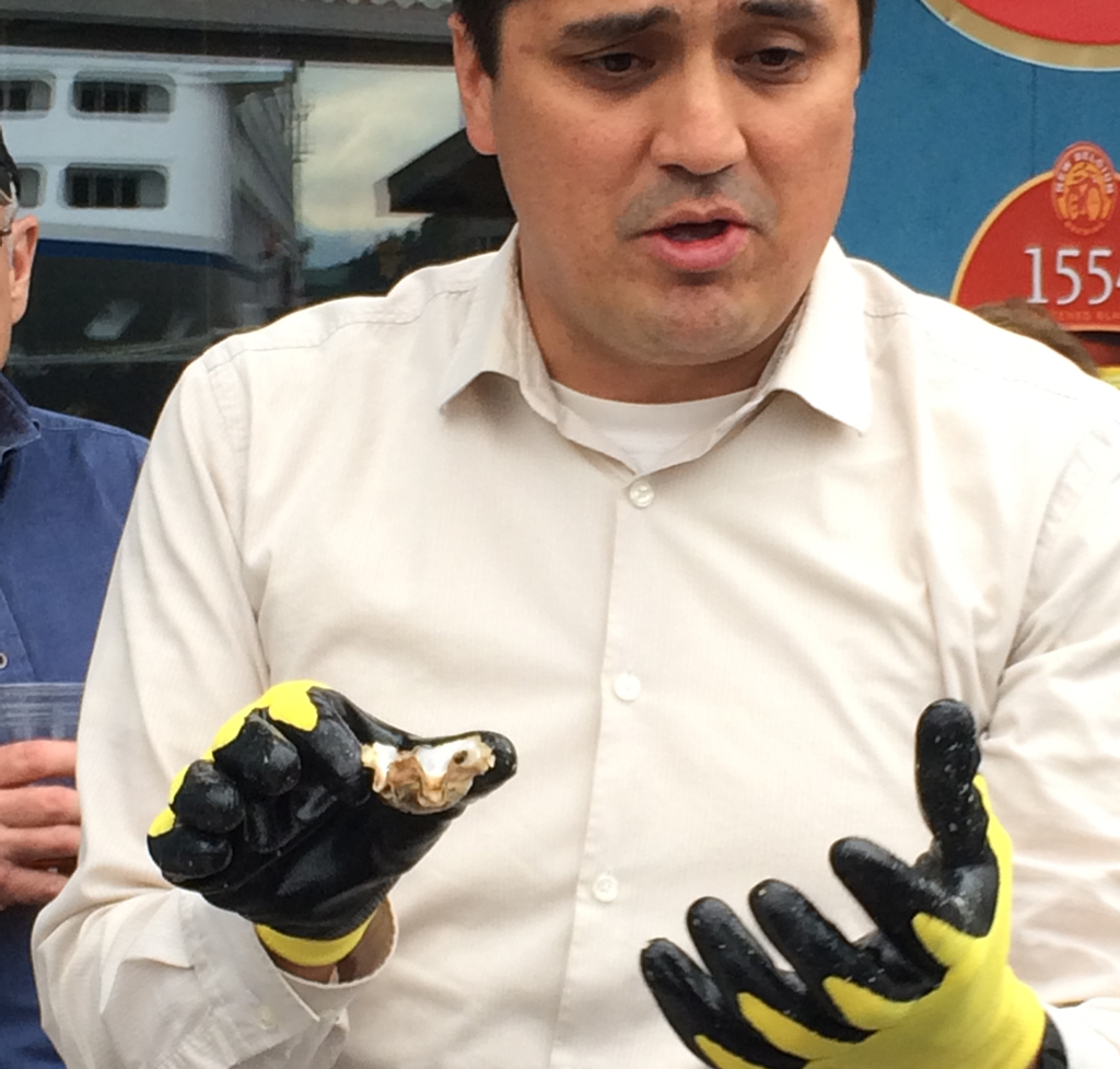Anthony Lindoff, mariculture program manager for Haa Aaní, teaches volunteers how to shuck oysters.