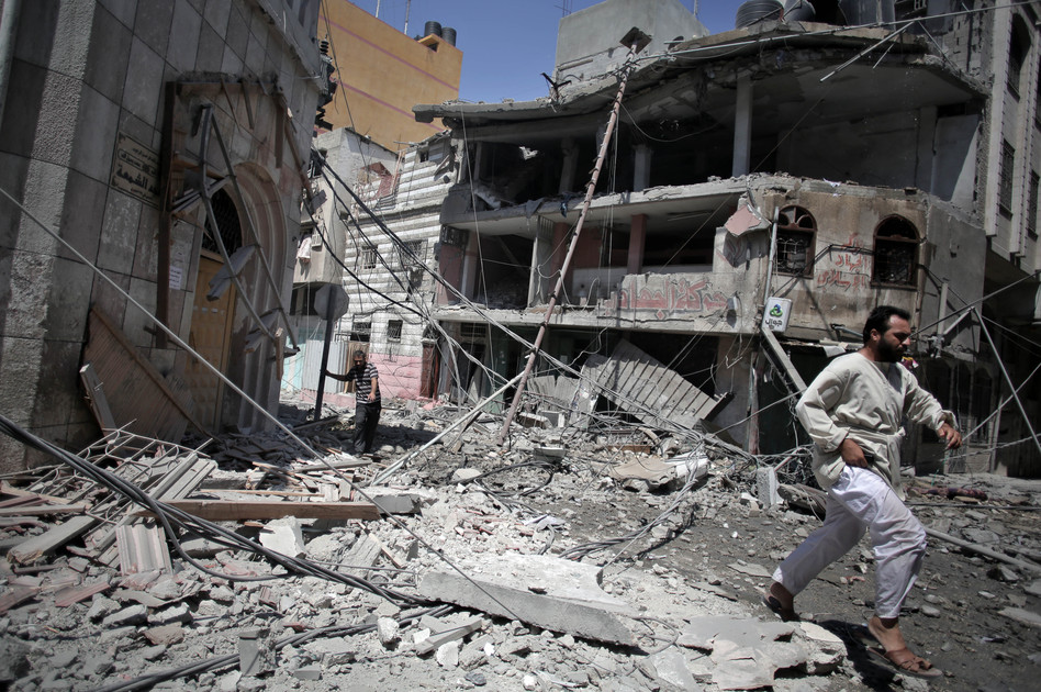 Palestinians walk through the rubble of houses in Gaza City minutes after they were hit in an Israeli strike on Wednesday. Khalil Hamra/AP
