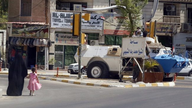 An Iraqi woman and child walk toward an Iraqi security armored personnel carrier on a Baghdad street, a sign of the political showdown between incumbent Prime Minister Nouri al-Maliki and those calling for his tenure to end. Sabah Arar/AFP/Getty Images