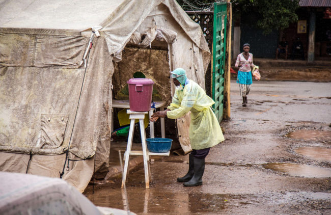 A health worker cleans his hands with chlorinated water before entering a Ebola screening tent, at a government hospital in Kenema, Sierra Leone, Monday. The World Health Organization cites 1,848 cases of the deadly disease across West Africa. Michael Duff/AP