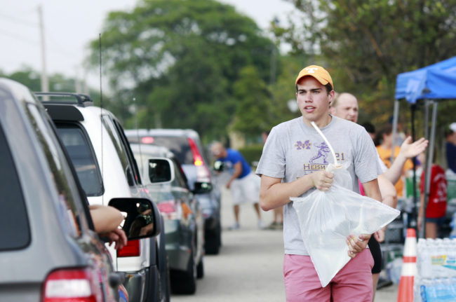 Grant Buehrer, a student at Ohio State University, volunteers to load a 5-pound bag of fresh drinking water into a vehicle on Sunday. Haraz N. Ghanbari/AP