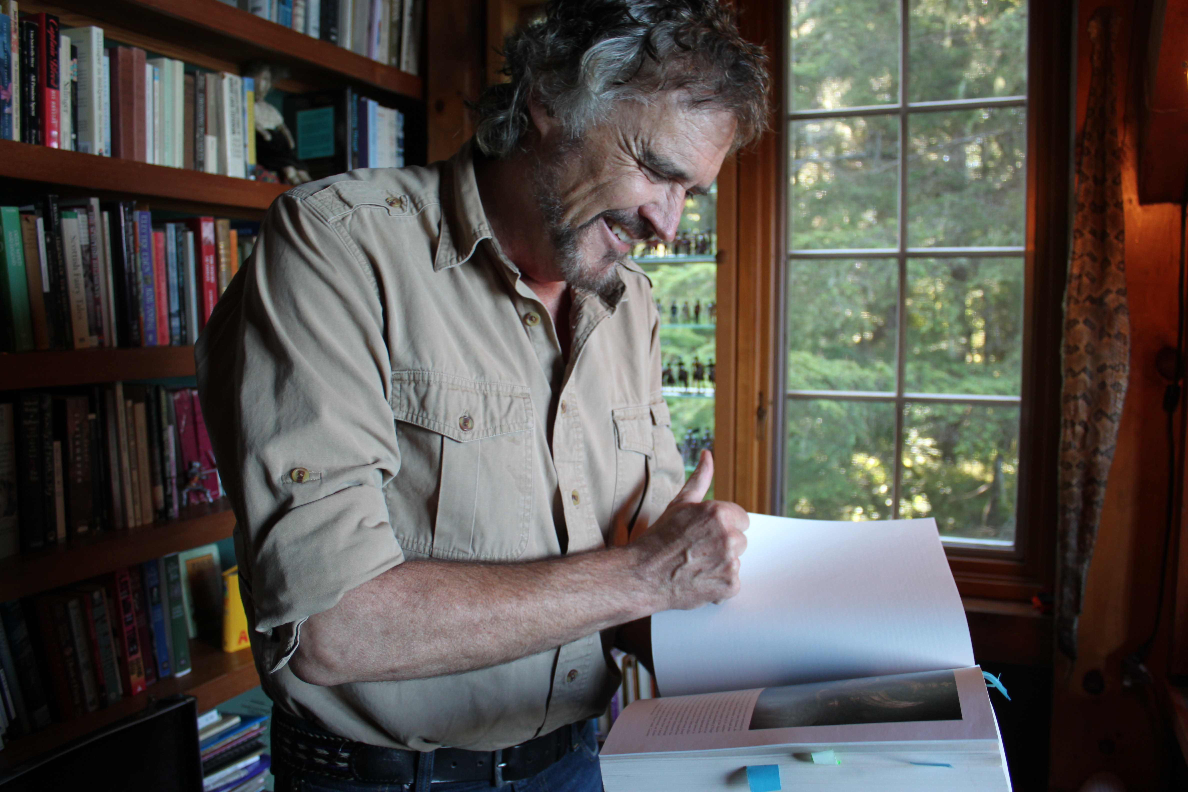 At home a day after Dick Dauenhauer died, Juneau playwright Dave Hunsaker flips through his copy of "Anóoshi Lingít Aaní Ká/Russians in Tlingit America: The Battles of Sitka, 1802 and 1804." (Photo by Lisa Phu/KTOO)