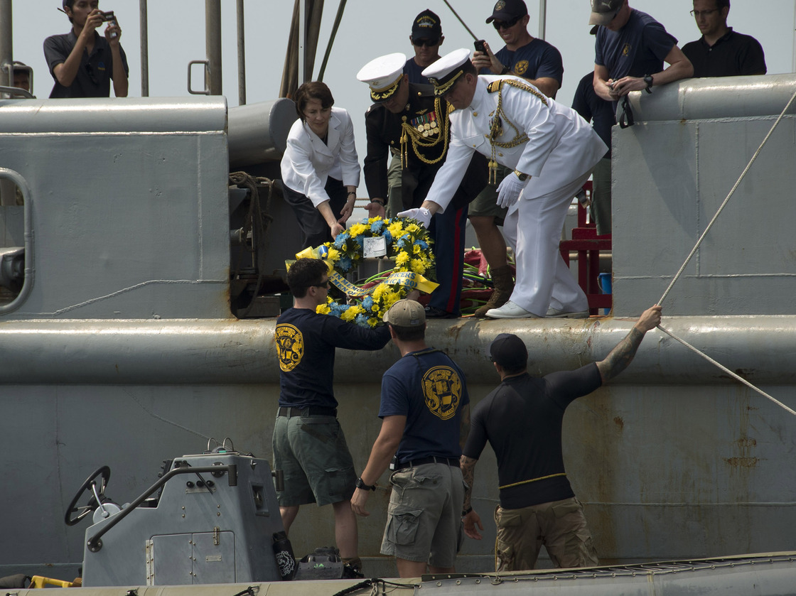 Deputy Chief of Mission (Jakarta, Indonesia) Kristen Bauer (top left), Capt. Richard Stacpoole (top right), and Marine Lt. Col. Miguel Avila pass a wreath to sailors, assigned to Mobile Diving Salvage Unit One, during a wreath-laying ceremony for the sunken Navy vessel USS Houston. Mass Communication Specialist 3rd Class Christian Senyk/U.S. Navy