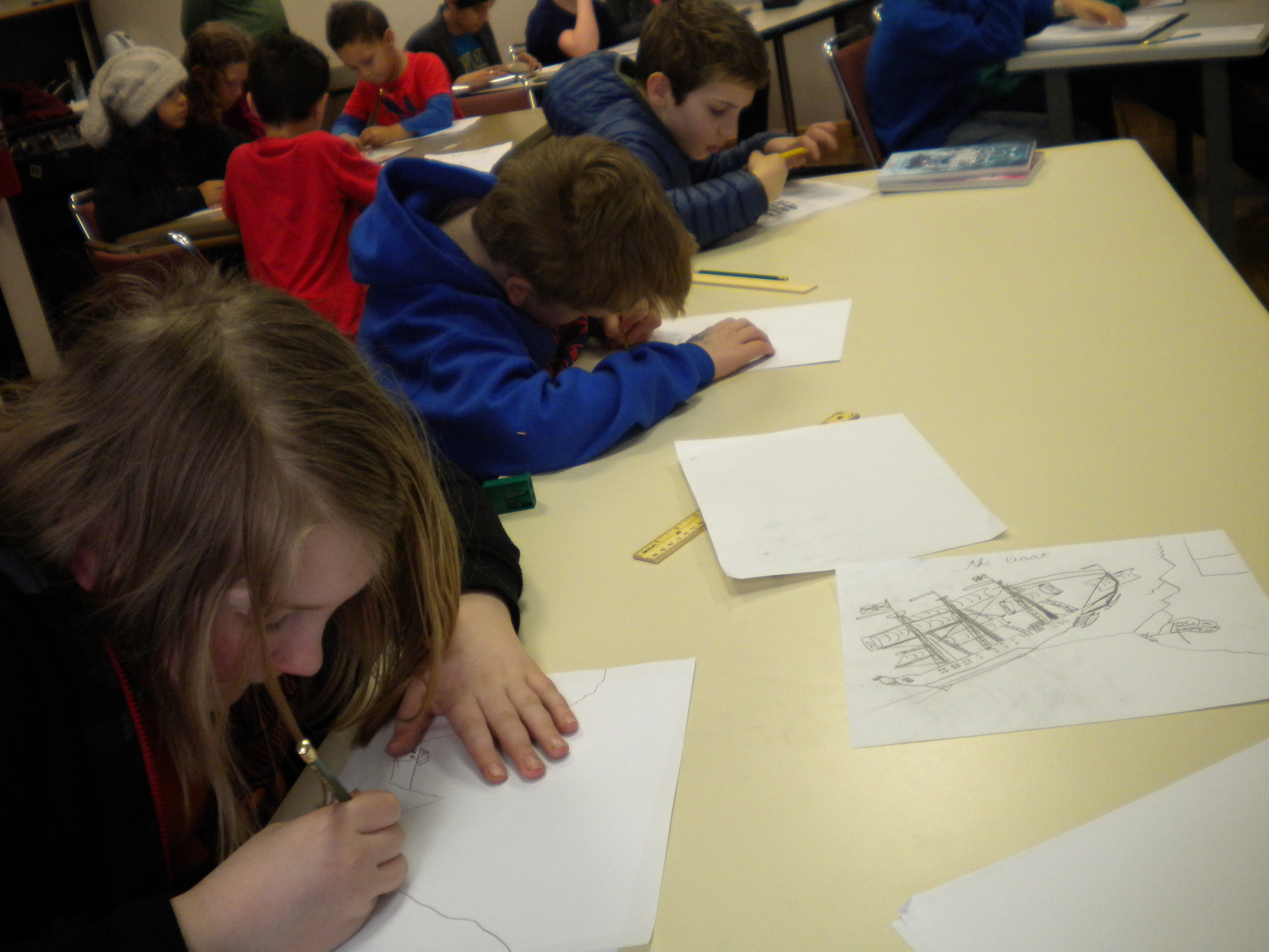 (Xander Love, left, sketches a robot at a drawing workshop in the Douglas Public Library on Saturday. About 30 school kids attended to learn about the process of creating a graphic novel from Kazu Kibuishi. Photo by Kevin Reagan/ KTOO)