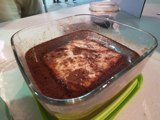 A small absorbent pad soaks up simulated oil, corn oil and chocolate powder, during a demonstration at the open house. (Photo by Matt Miller/KTOO)