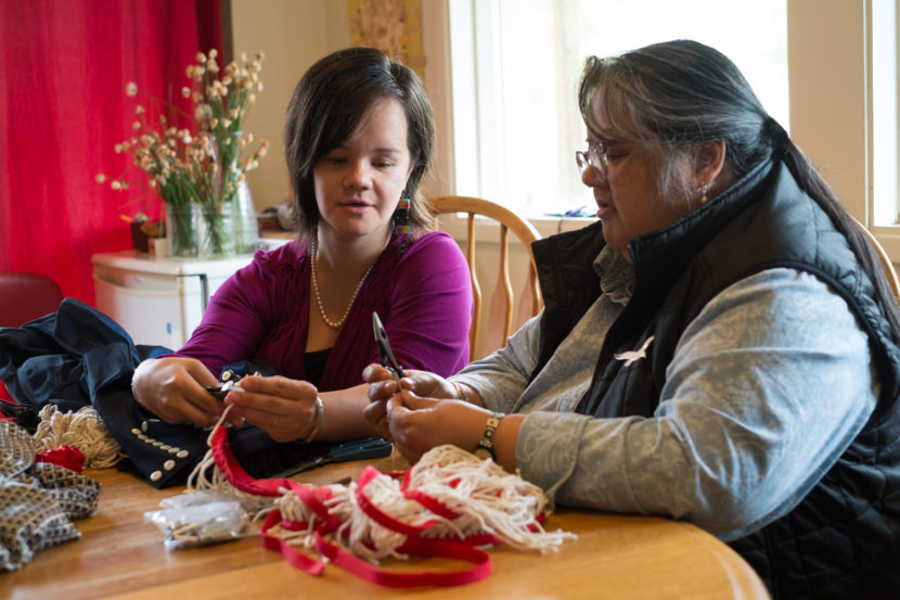 Lily Hope and Deanne Lampe attach silver cones to Chilkat fringe for their piece in the Sealaska Heritage Institute Native Fashion Show. (Photo by Annie Bartholomew/KTOO)
