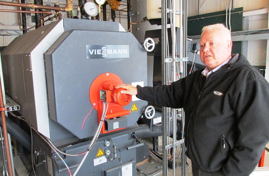 Airport Manager Mike Carney stands next to the Ketchikan International Airport’s new biomass wood-pellet boiler last summer. (File photo by Leila Kheiry/KRBD)