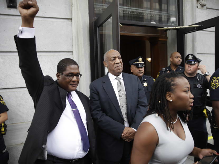 Bill Cosby looks on as spokesman Andrew Wyatt triumphantly raises his fist outside the Montgomery County Courthouse in Norristown, Pa., on Saturday. Cosby's legal and publicity team treated the mistrial as a victory, though prosecutors immediately said they plan to retry the case.