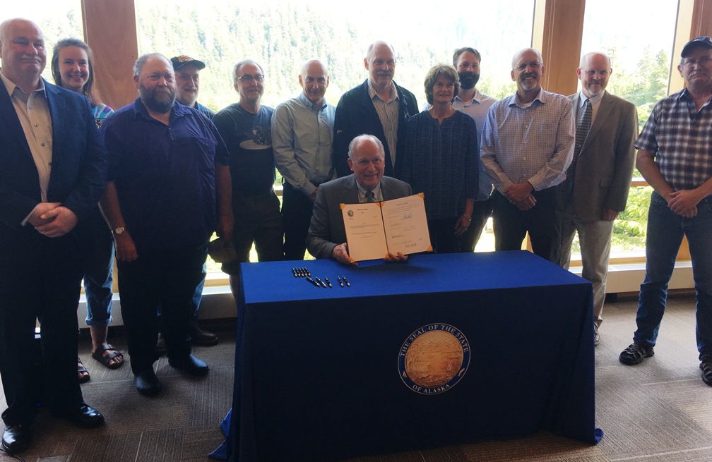 Gov. Bill Walker hold up a signed Senate Bill 88, the Alaska Mental Health Trust land exchange. (Photo by Leila Kheiry/KRBD)