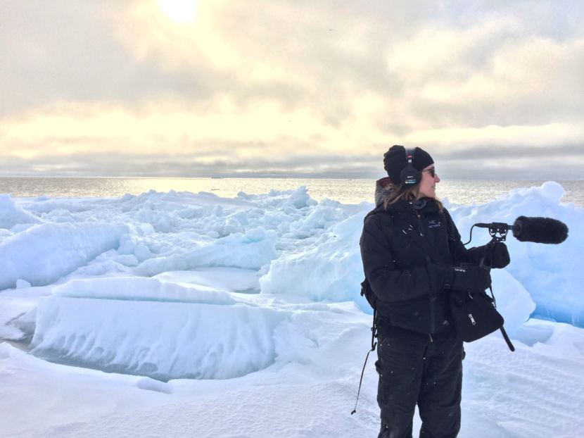 Ravenna Koenig of Alaska's Energy Desk/KTOO stands on the leading edge of the sea ice while recording sound for a story about Arctic Field School. (Photo courtesy of Lindsay Cameron)