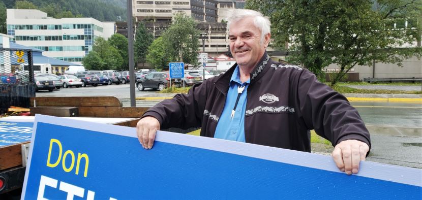 Don Etheridge holds up one of the campaign signs he's hauling in his truck outside KTOO in Juneau on Aug. 7, 2018.