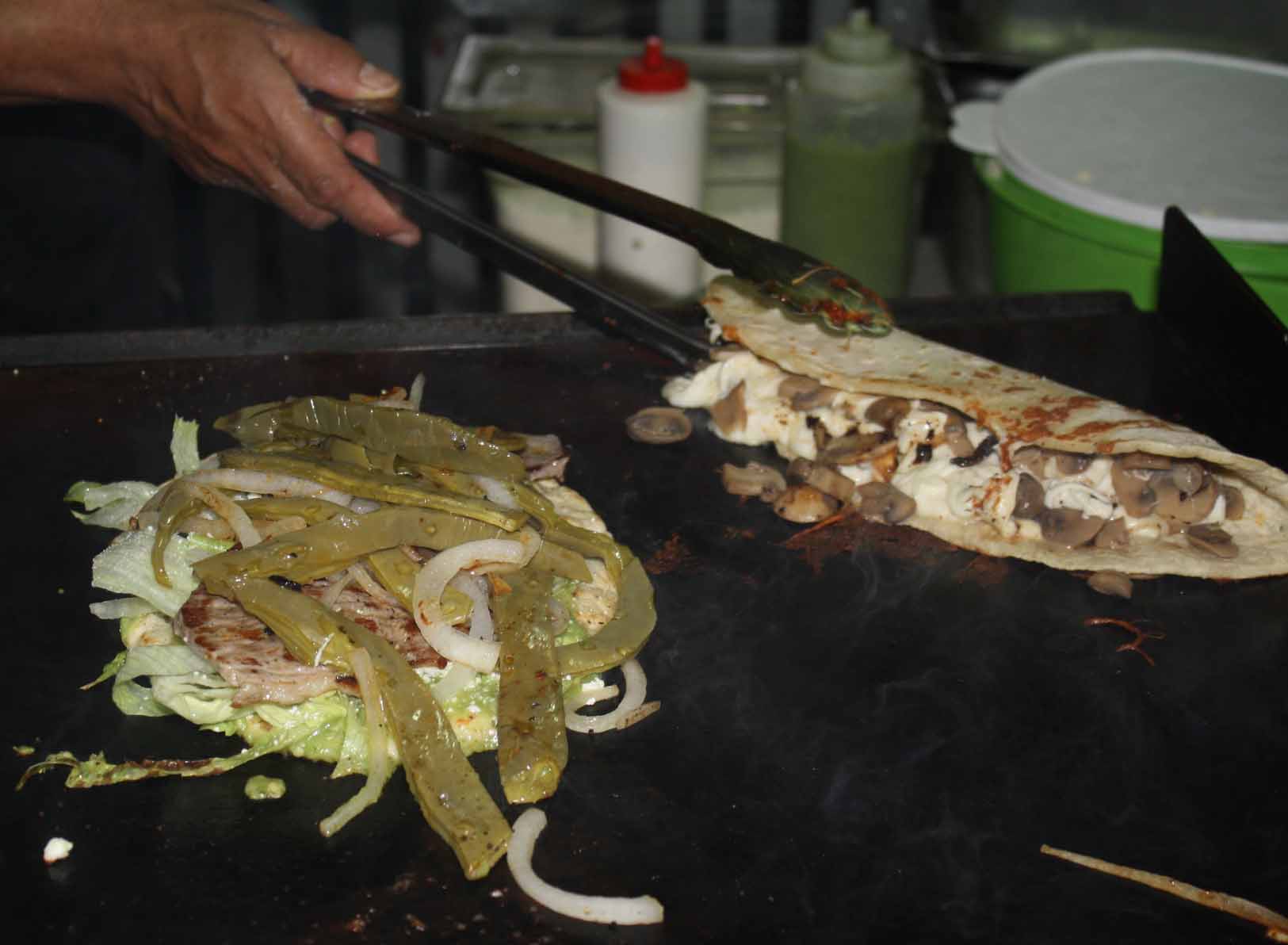Quesadillas y huaraches Y para chuparse los dedos, llenos de salsa, una exquisita quesadilla de hongos sobre la parrila y un huarache cubierta de nopales.