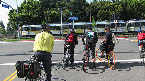 Riders wait out the traffic light at the intersection of Exposition and Harcourt as Expo Line Passes By.