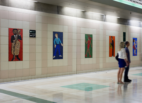 A view of one mezzanine wall at Civic Center Station picturing five of 52 individual glass mosaics comprising the artwork by Faith Ringgold titled People Portraits: in Creativity, Performing, Sports and Fashion.