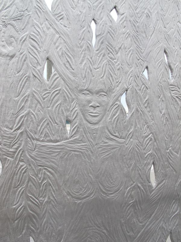 Detail of Paraje. The sculpture’s west face depicts a willow tree, while on the east face a willow spirit emerges mysteriously from the tree. The folds of the willow spirit’s dress become the roots of the tree and the spirit’s upheld arms become branches.